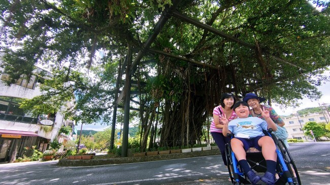 名護市ひんぷんがじゅまる前で車椅子ユーザー含む親子3世代の記念撮影